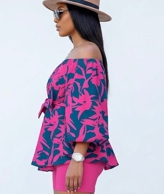 The Bloom Two-Piece Set is confidence in print form. A vibrant hot pink floral pattern bursts across a deep navy off-shoulder peplum top with voluminous balloon sleeves — cinched at the waist with a matching belt tie and paired with solid hot pink biker shorts that complete the look with intention.
