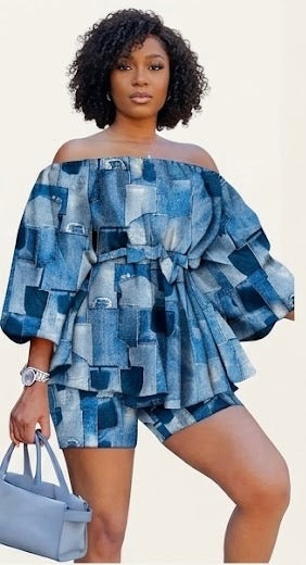 The Blueprint Two-Piece Set is a cultural statement dressed as a fit. A bold patchwork denim print — rendered in varying shades of blue across an off-shoulder peplum top with dramatic balloon sleeves — cinched at the waist with a matching belt tie and paired with coordinating denim-print biker shorts that complete the look from top to bottom.