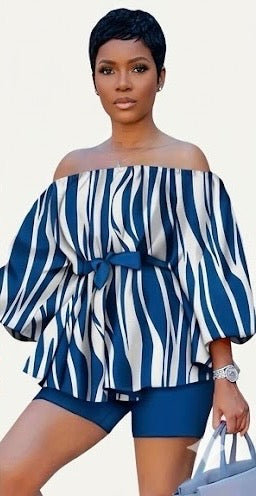 The Current Two-Piece Set is momentum you can wear. A striking navy and white wave-stripe print flows across an off-shoulder peplum top with dramatic balloon sleeves — cinched at the waist with a matching belt tie and grounded by coordinating navy biker shorts.