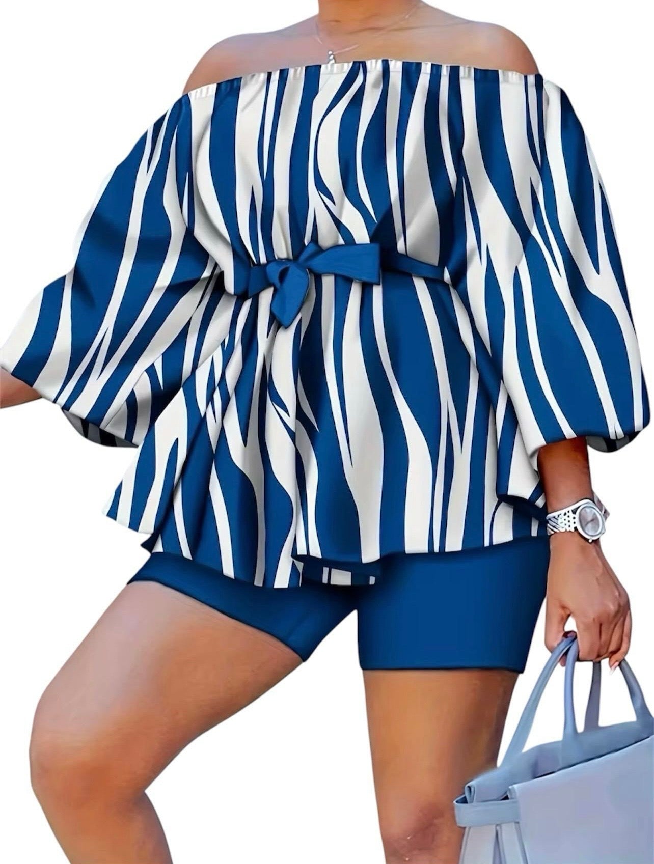 The Current Two-Piece Set is momentum you can wear. A striking navy and white wave-stripe print flows across an off-shoulder peplum top with dramatic balloon sleeves — cinched at the waist with a matching belt tie and grounded by coordinating navy biker shorts.