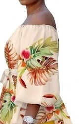 The Golden Hour Two-Piece Set is the calm confidence of a perfect moment — bottled in fabric. A warm champagne base blooms with coral, green, and red tropical florals across an off-shoulder peplum top with soft balloon sleeves — cinched with a matching belt tie and paired with rich gold biker shorts that glow against every skin tone.