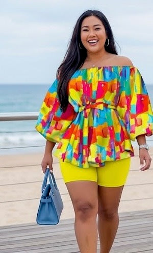 The Palette Two-Piece Set is for the woman who lives in full color. A vibrant abstract paint-block print in yellow, orange, teal, pink, and purple cascades across an off-shoulder peplum top with voluminous balloon sleeves — cinched at the waist with a matching belt tie and anchored by bold yellow biker shorts that pull the whole canvas together.