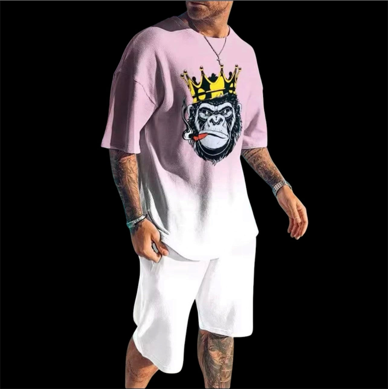 A soft pink gradient fades to white across an oversized crewneck tee anchored by a bold crowned gorilla graphic — street art energy meets resort ease. Paired with clean white shorts that let the top lead without competition.
