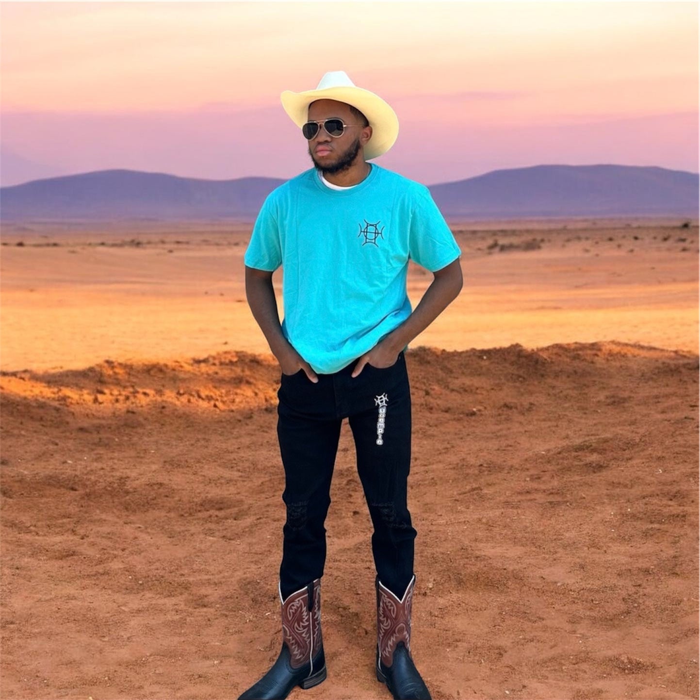 The Mark Crew in Blue doesn’t blend into the background — it owns it. A striking turquoise 100% cotton crewneck carries the TAUGEMPIE crest mark on the left chest and the full signature logo graphic across the back in vivid blue, green, and gold.
