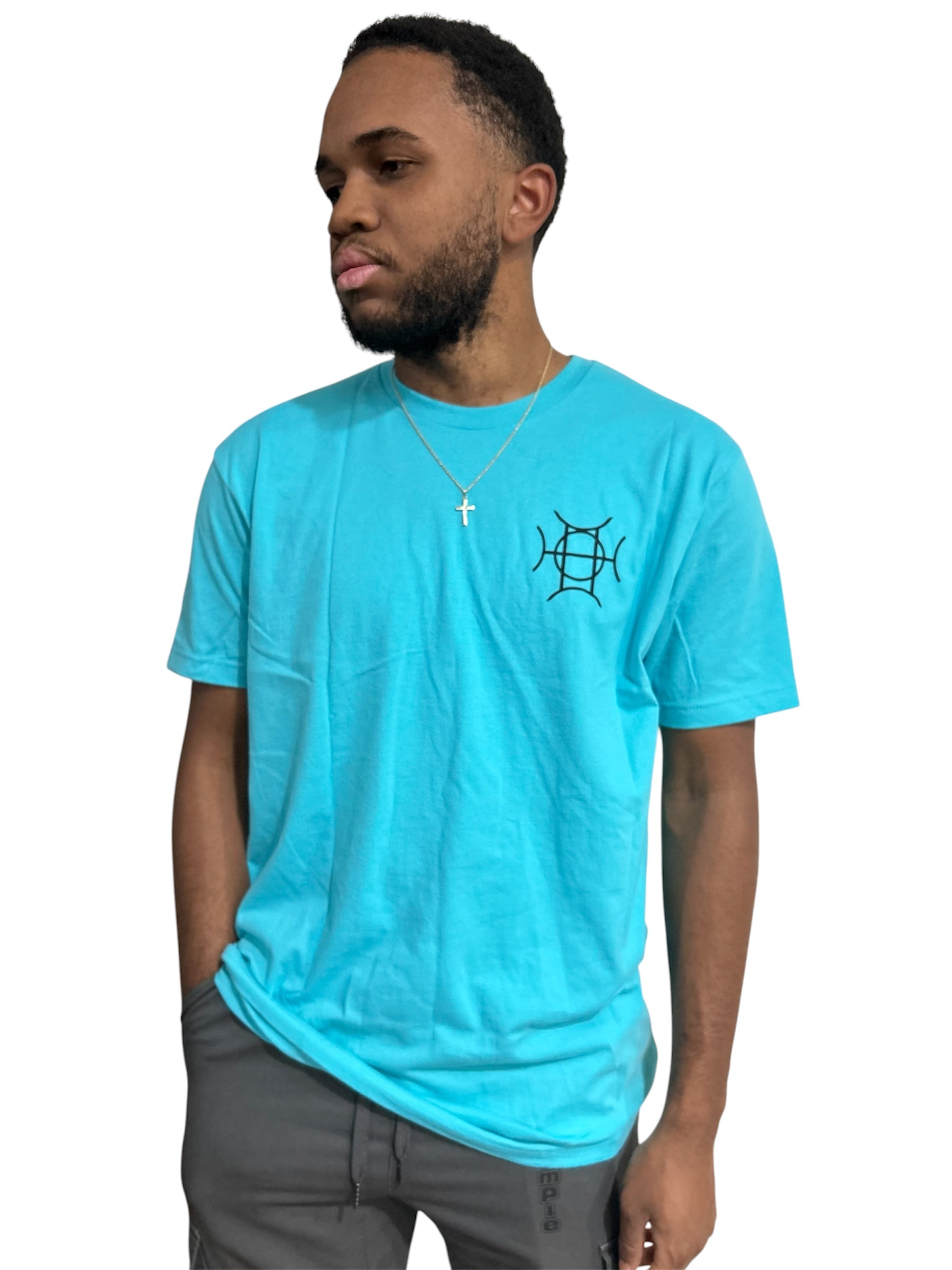 The Mark Crew in Blue doesn’t blend into the background — it owns it. A striking turquoise 100% cotton crewneck carries the TAUGEMPIE crest mark on the left chest and the full signature logo graphic across the back in vivid blue, green, and gold.
